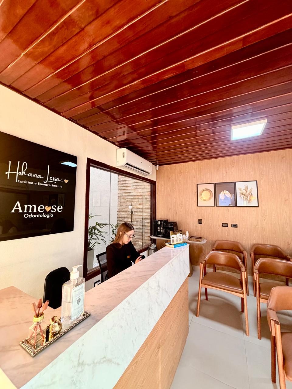 Balcão da recepção da clínica, com sala de espera ao fundo